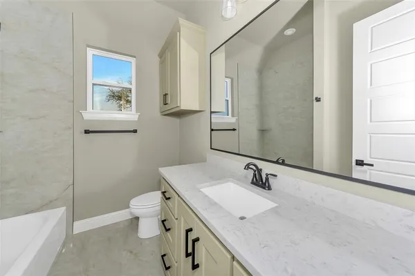 a bathroom with a granite countertop sink a large mirror a toilet and a bathtub