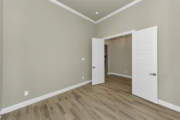 a view of an empty room with wooden floor and closet