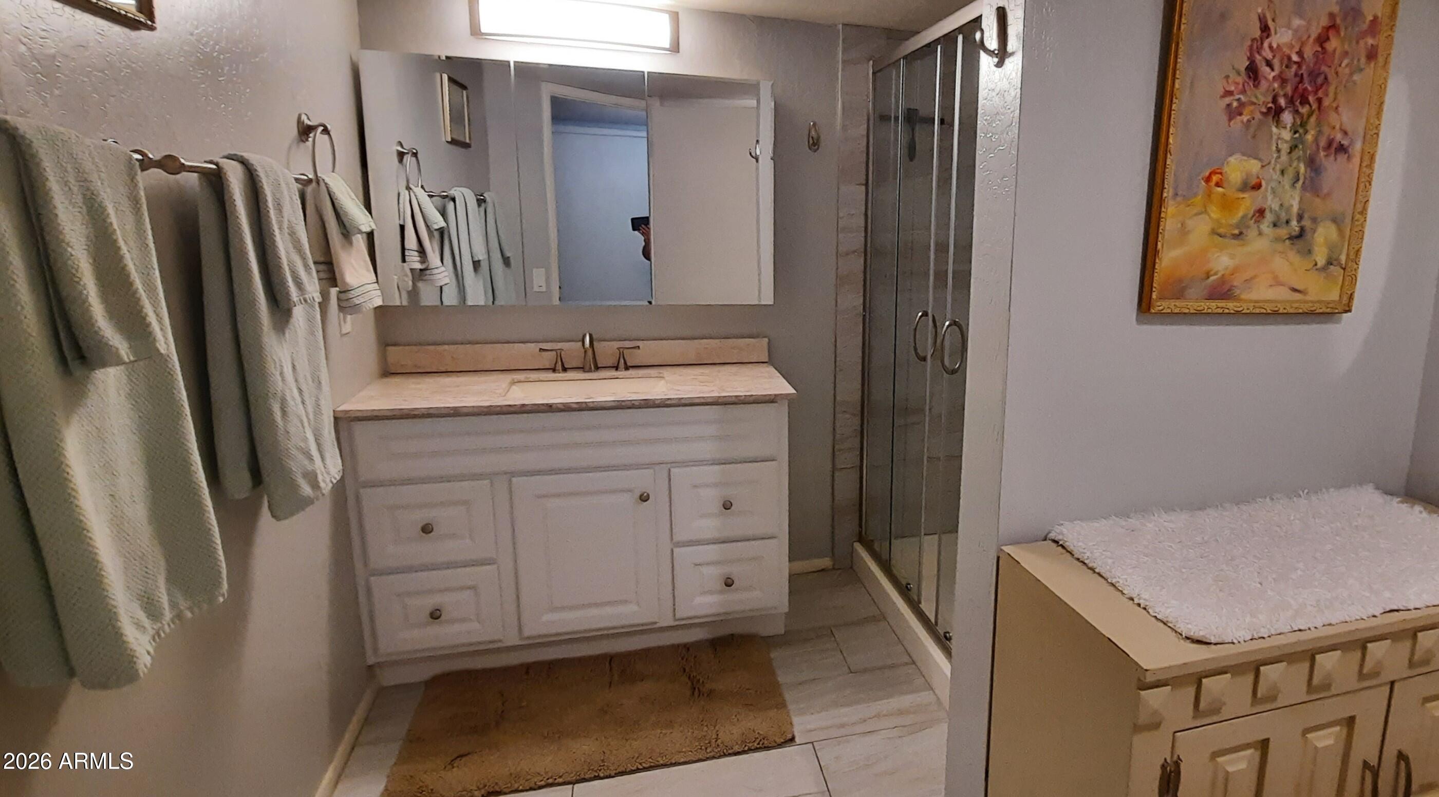 12221 West Bell Road, Unit 149 Surprise, AZ 85378 - Photo 17 of 28 a bathroom with a granite countertop sink a mirror a vanity and a shower
