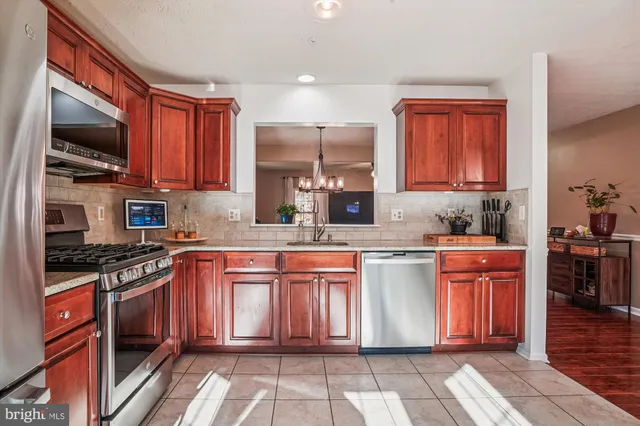 a kitchen with stainless steel appliances granite countertop a stove top oven a sink dishwasher a dining table and chairs with wooden floor