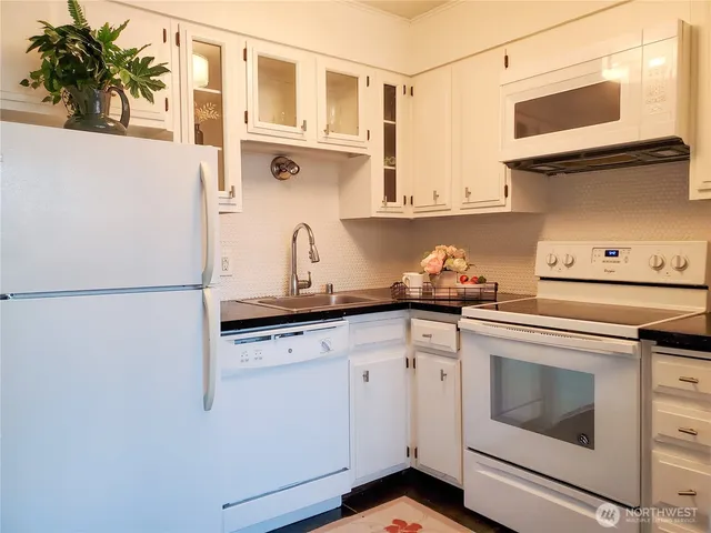 a kitchen with granite countertop white cabinets and white appliances