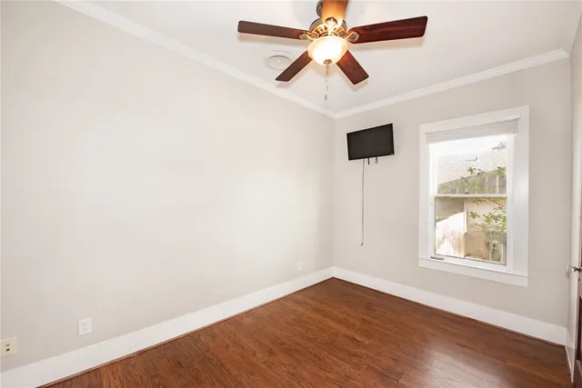an empty room with wooden floor chandelier fan and windows
