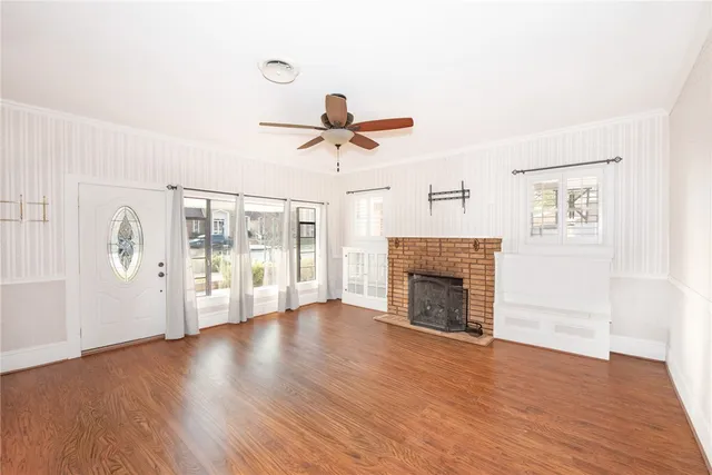 an empty room with wooden floor a fireplace and windows