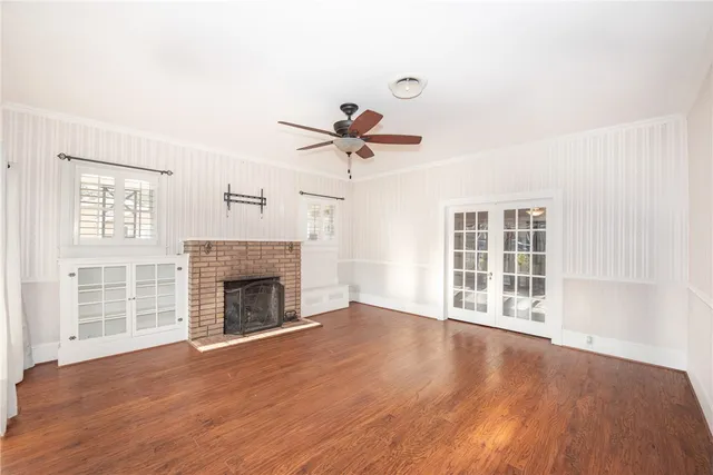 an empty room with wooden floor fireplace and windows
