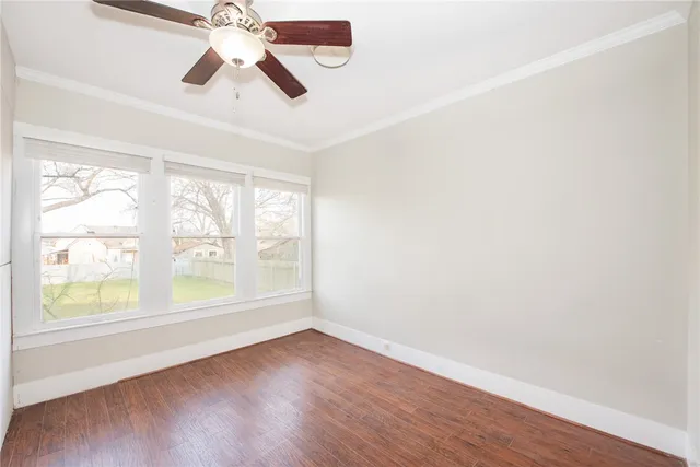 an empty room with wooden floor fan and windows