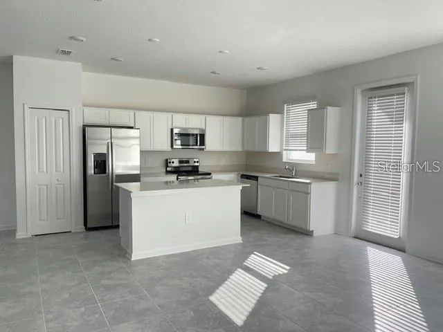 a kitchen with white cabinets and stainless steel appliances