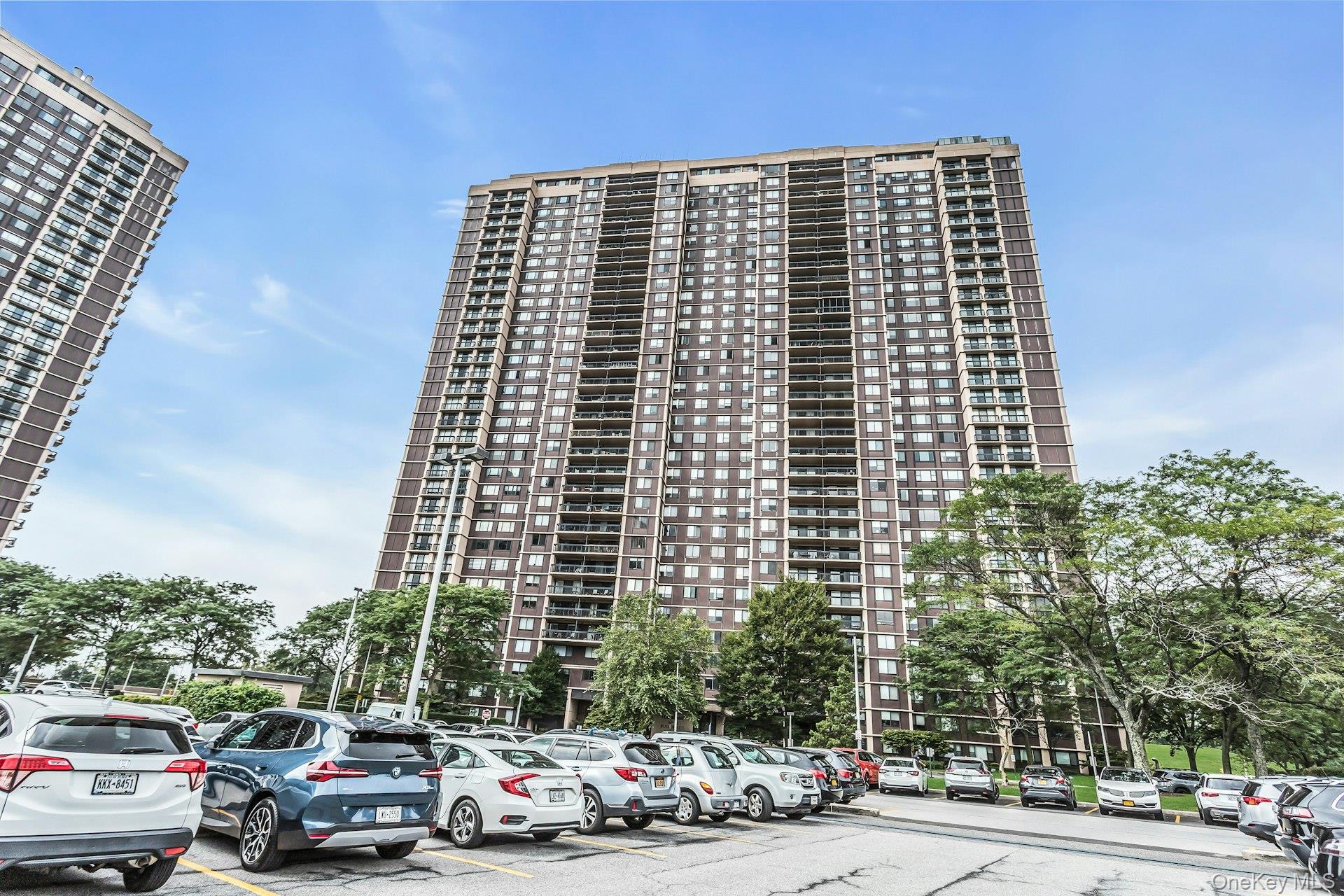 269 Grand Central Parkway, Unit 27T Queens, NY 11005 - Photo 2 of 43 a front view of a building with lot of cars and trees