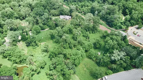 an aerial view of residential house with outdoor space and trees all around