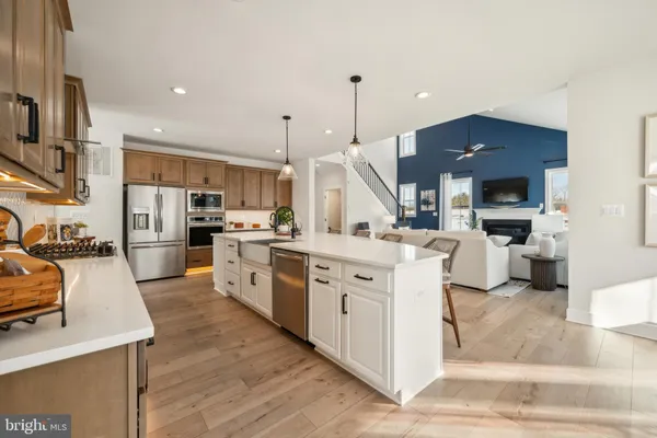 a large kitchen with stainless steel appliances kitchen island granite countertop a stove a sink a refrigerator and a fireplace