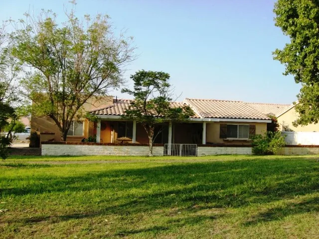 a front view of a house with a garden and trees