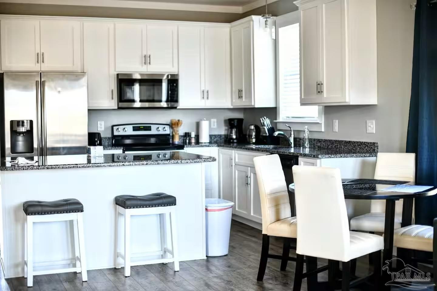 5446 Medina Road Pensacola, FL 32507 - Photo 3 of 11 a kitchen with stainless steel appliances granite countertop a table chairs microwave and sink