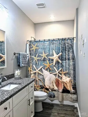 a bathroom with a granite countertop sink and a toilet