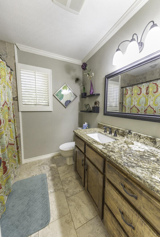 3620 93rd Street Lubbock, TX 79423 - Photo 23 of 33 a bathroom with a granite countertop sink a toilet and a window