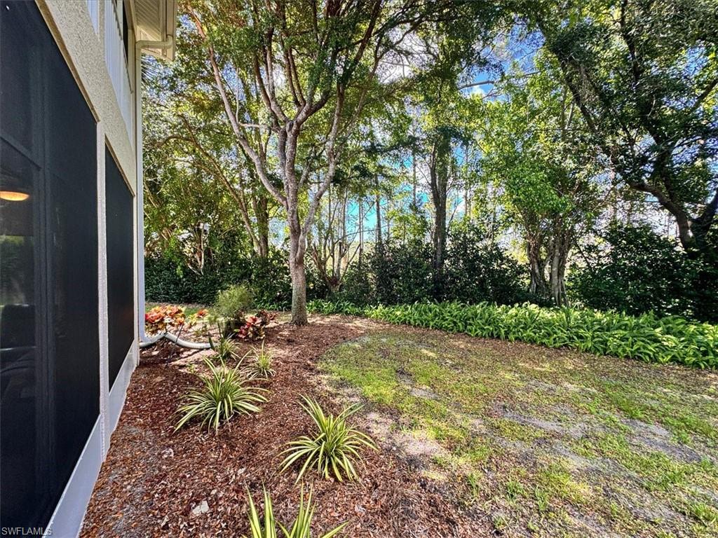 873 Carrick Bend Circle, Unit 101 Naples, FL 34110 - Photo 18 of 42 a view of backyard with table and chairs plants and large trees