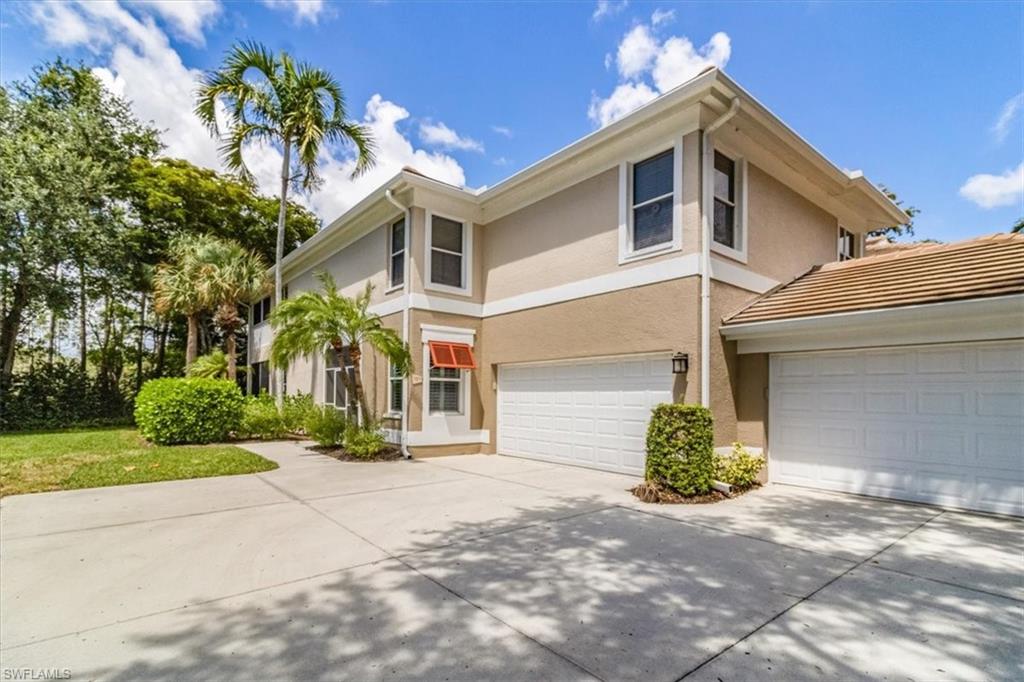 873 Carrick Bend Circle, Unit 101 Naples, FL 34110 - Photo 2 of 42 a front view of a house with a yard and a garage