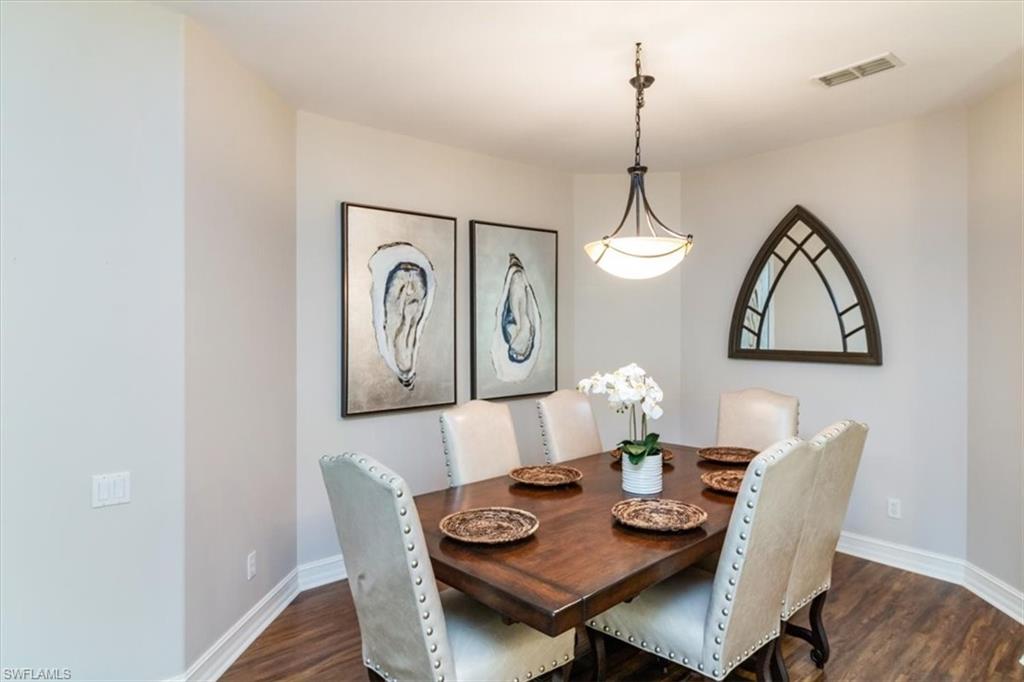 873 Carrick Bend Circle, Unit 101 Naples, FL 34110 - Photo 21 of 42 a view of a dining room with furniture wooden floor and a chandelier