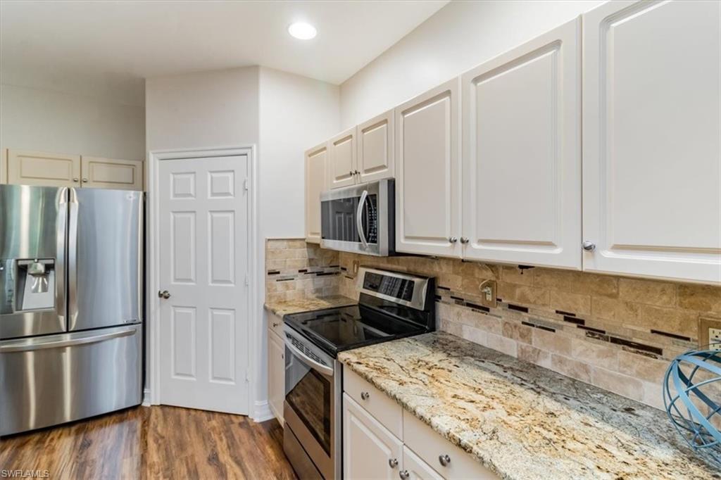873 Carrick Bend Circle, Unit 101 Naples, FL 34110 - Photo 22 of 42 a kitchen with granite countertop a refrigerator stove and microwave