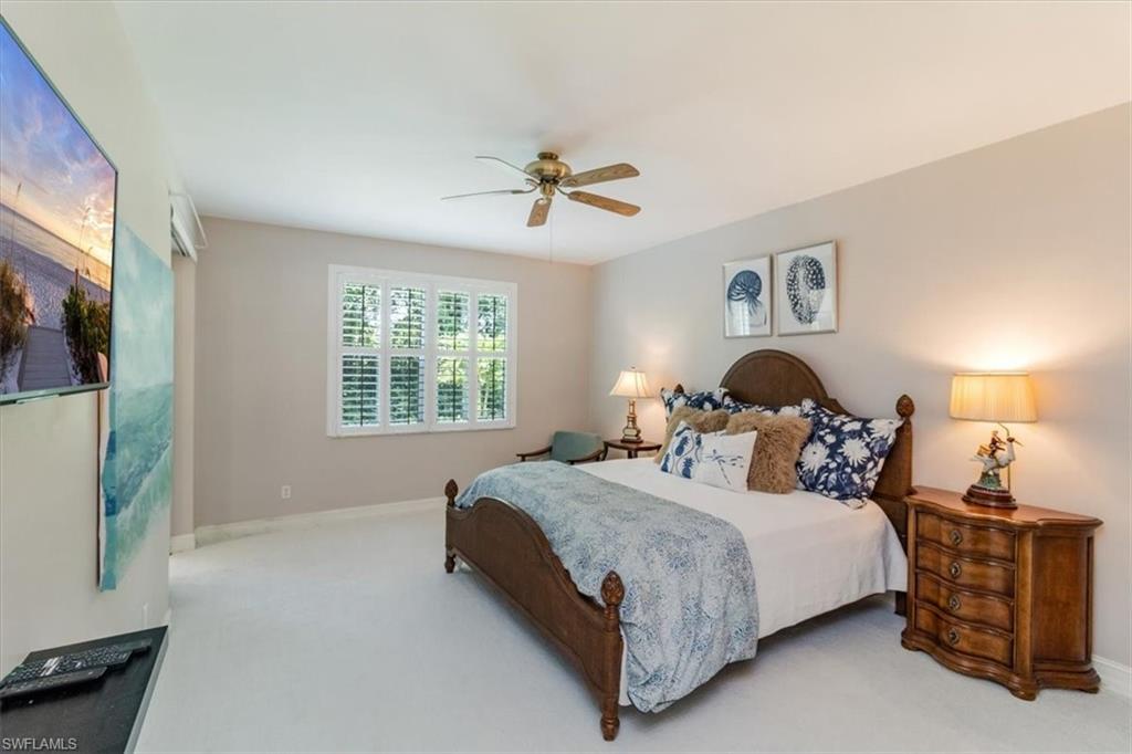 873 Carrick Bend Circle, Unit 101 Naples, FL 34110 - Photo 25 of 42 a bedroom with a bed and a chandelier