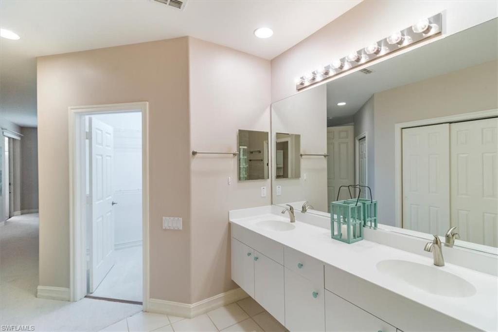 873 Carrick Bend Circle, Unit 101 Naples, FL 34110 - Photo 26 of 42 a bathroom with a double vanity sink and a mirror