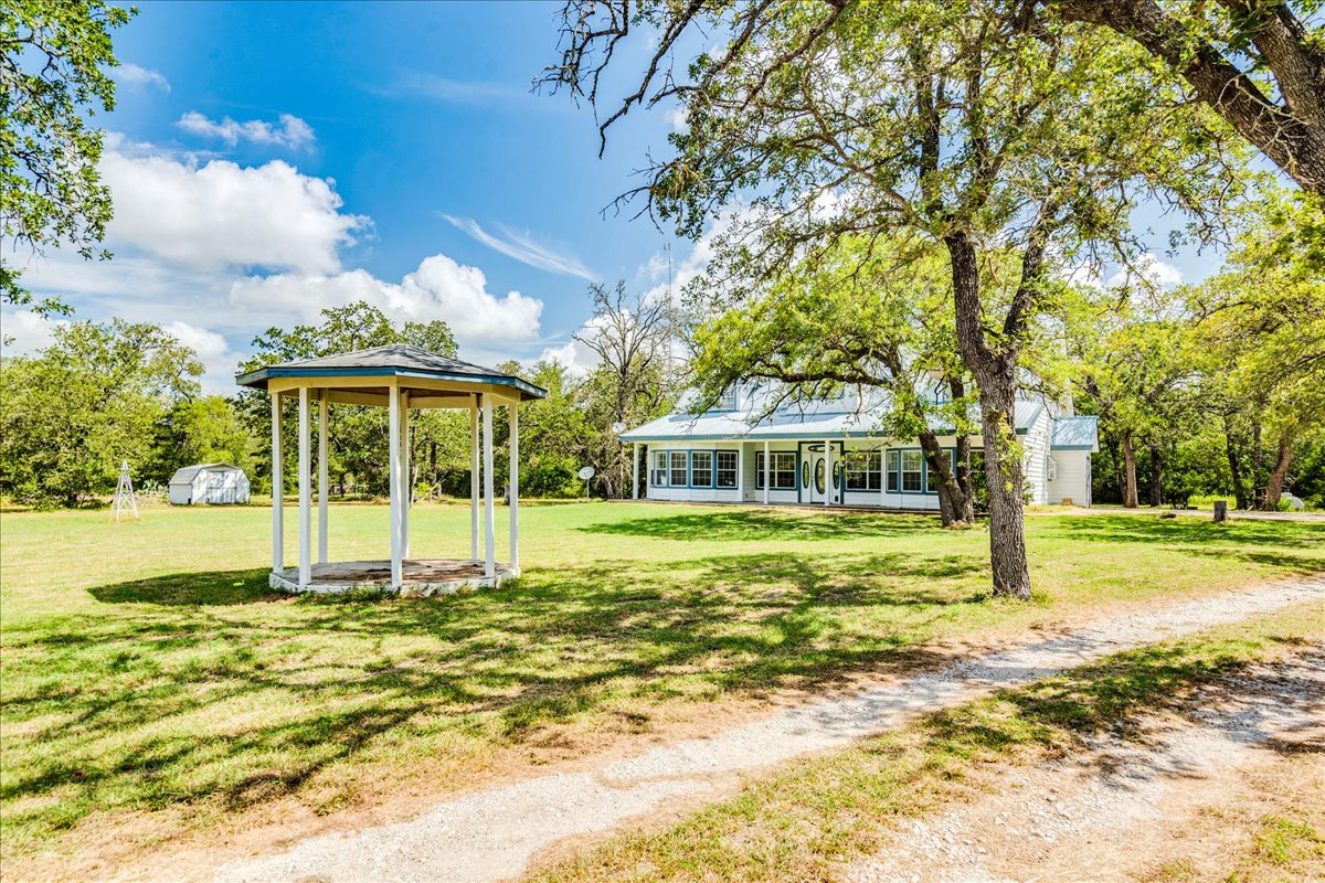 19106 Eyerley Road Manor, TX 78653 - Photo 39 of 40 A graceful gazebo complements the spacious yard, set against a backdrop of mature trees and a charming home.