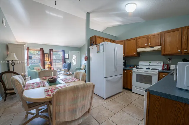 a kitchen with stainless steel appliances a refrigerator a stove a sink a dining table and chairs with wooden floor