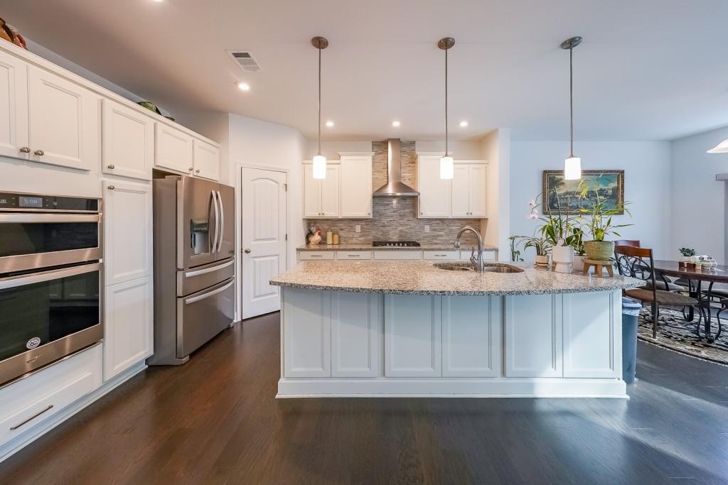 5116 Barton Pass Northwest Acworth, GA 30101 - Photo 11 of 42 a large kitchen with stainless steel appliances kitchen island granite countertop a stove a refrigerator and a wooden floor