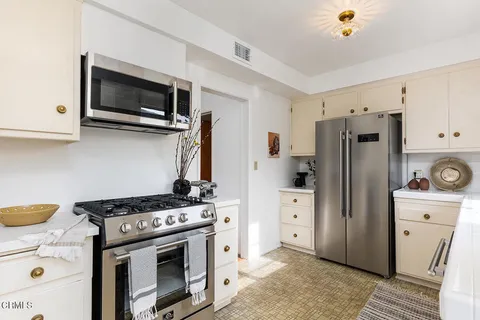 a kitchen with stainless steel appliances a refrigerator stove and white cabinets
