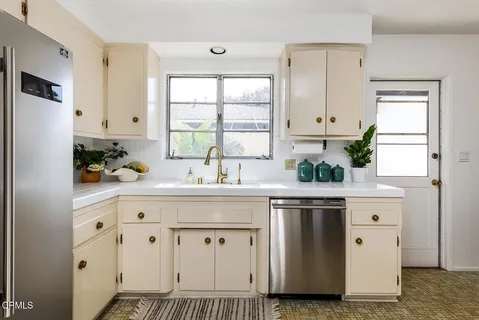 a kitchen with stainless steel appliances white cabinets and a window