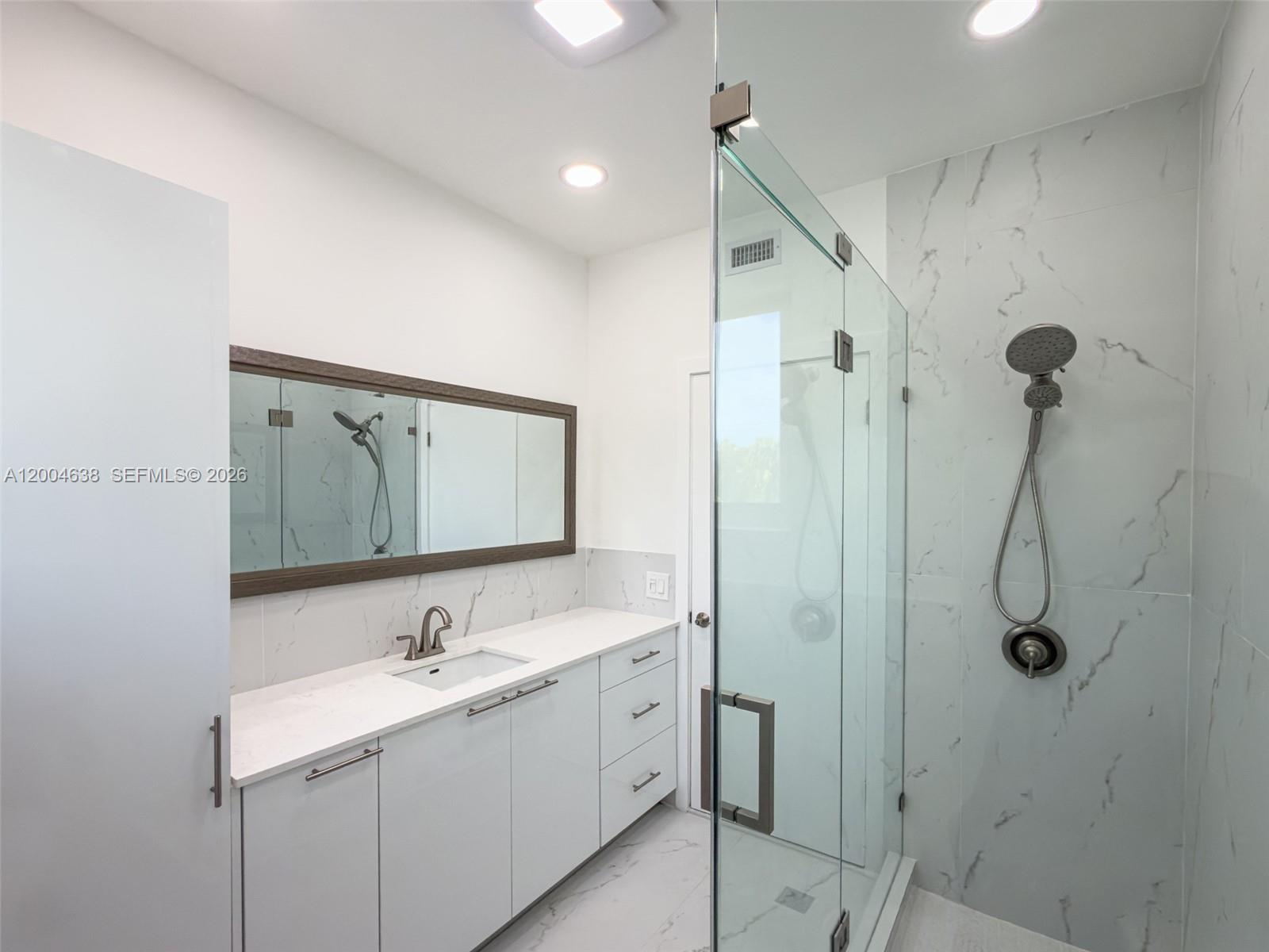 1690 Daytonia Road Miami Beach, FL 33141 - Photo 20 of 88 a bathroom with a double vanity sink a mirror and shower