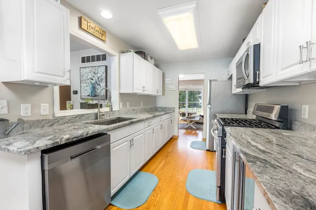 a kitchen with stainless steel appliances granite countertop a stove a sink and a white cabinets