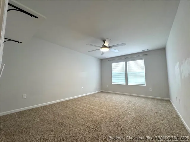 an empty room with a ceiling fan and a window