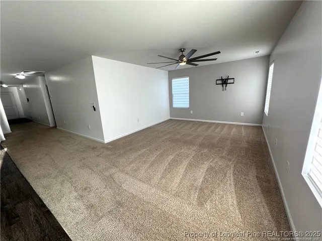 an empty room with windows and ceiling fan