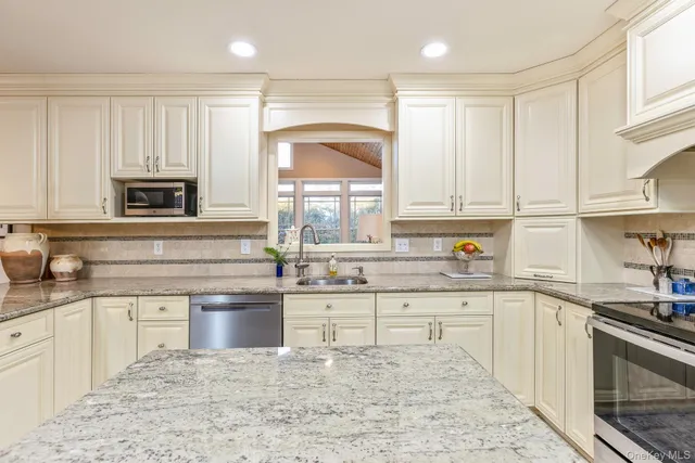 a kitchen with granite countertop a sink stainless steel appliances and cabinets