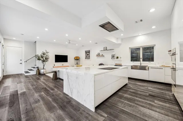 a white kitchen with a sink and a large window