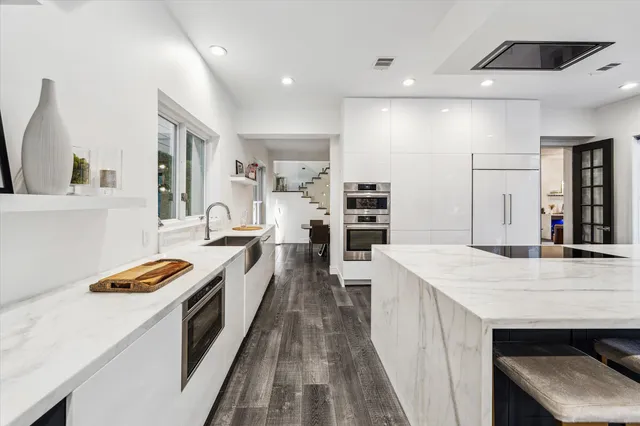 a large kitchen with kitchen island a sink stove and wooden floor