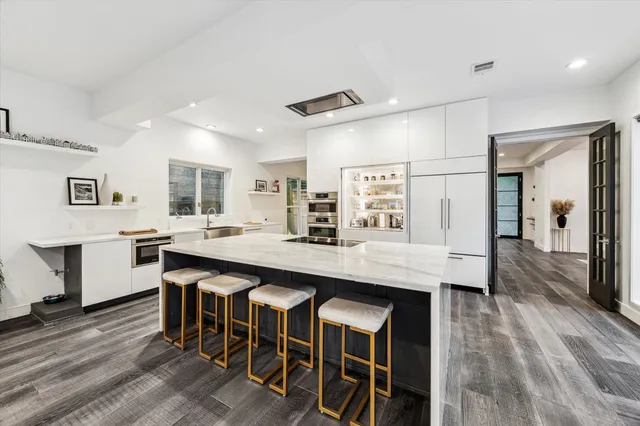 a kitchen with stainless steel appliances granite countertop a table chairs refrigerator and sink