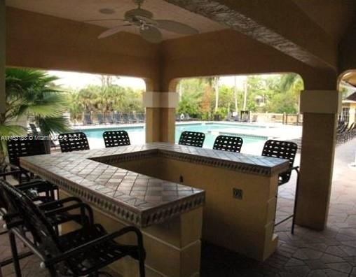 4055 West McNab Road, Unit H303 Pompano Beach, FL 33069 - Photo 27 of 29 a view of a patio with table and chairs under an umbrella with a small yard