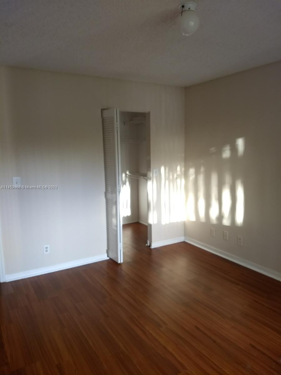 4055 West McNab Road, Unit H303 Pompano Beach, FL 33069 - Photo 4 of 29 an empty room with wooden floor and windows