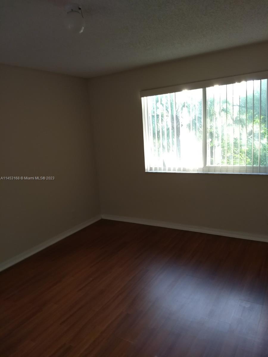 4055 West McNab Road, Unit H303 Pompano Beach, FL 33069 - Photo 9 of 29 a view of an empty room with wooden floor and a window