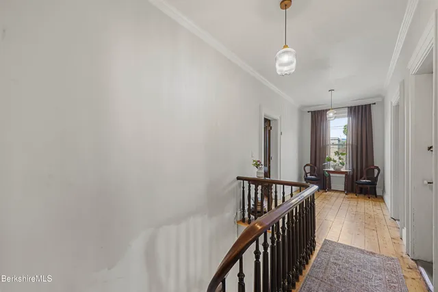 a view of a hallway with wooden floor and stairs