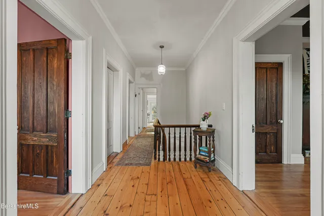 a view of a hallway with wooden floor and staircase