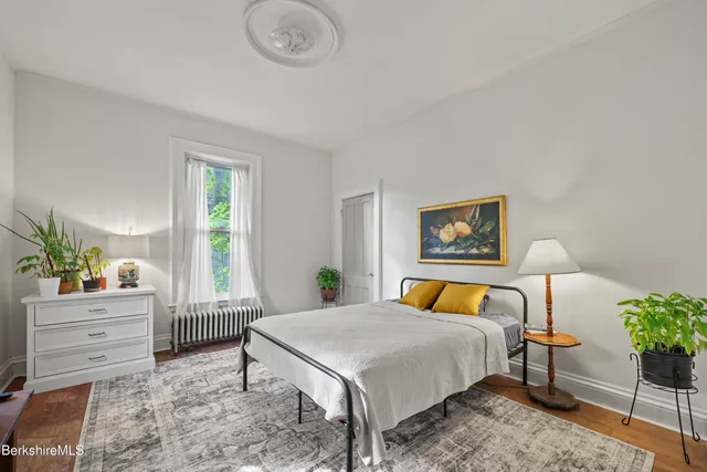 a bedroom with a bed a couch and potted plant on the dresser