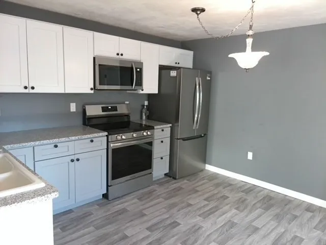 a kitchen with stainless steel appliances granite countertop a stove a refrigerator and a microwave