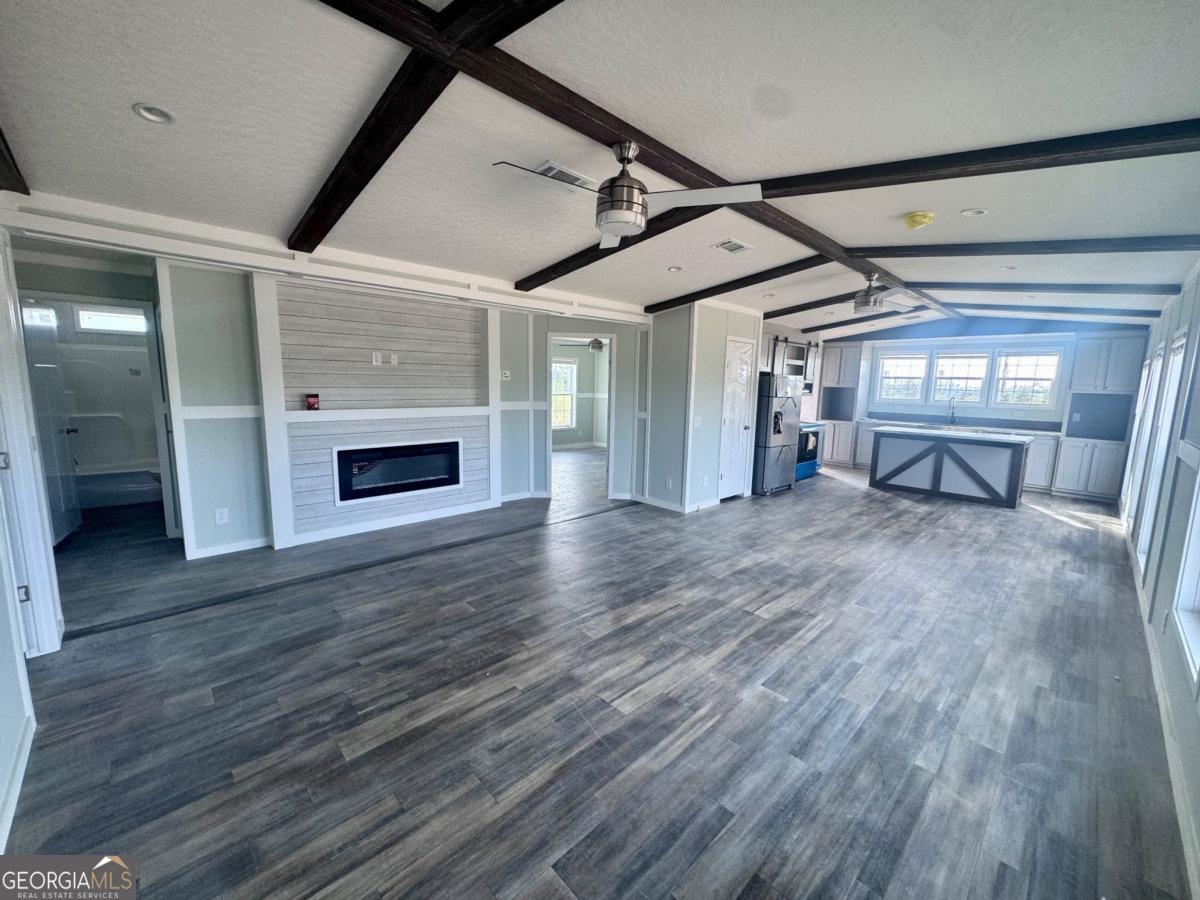 59 Long Leaf Road Hazlehurst, GA 31539 - Photo 6 of 19 a empty room with wooden floor fireplace and windows