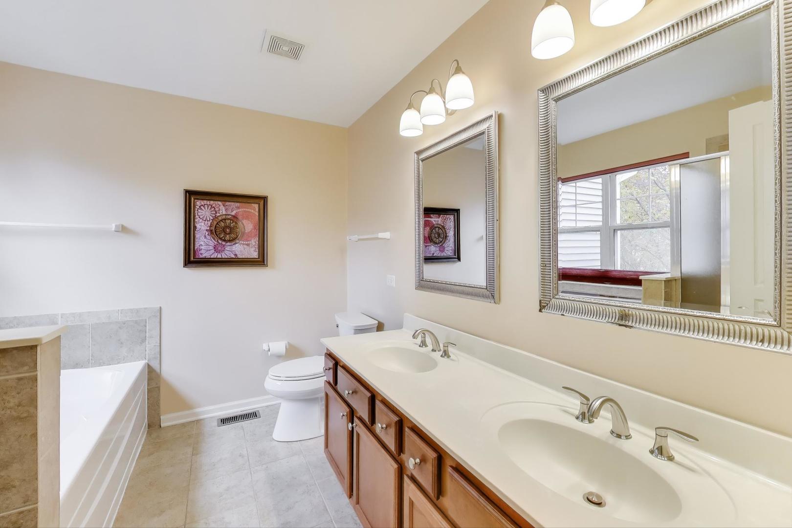 934 Tuscany Drive Streamwood, IL 60107 - Photo 22 of 45 a bathroom with a double vanity sink toilet and a mirror
