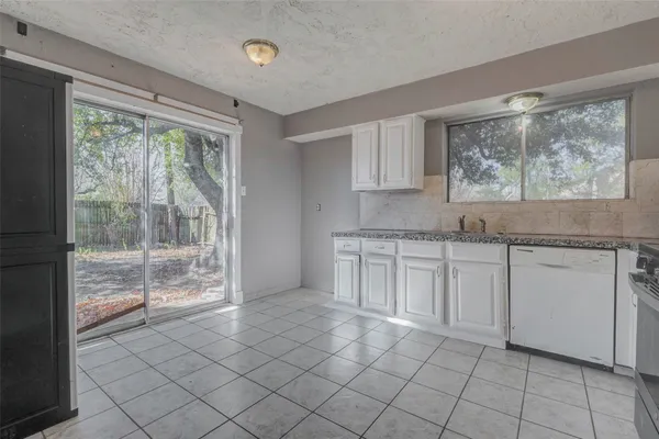 a kitchen with white cabinets and window