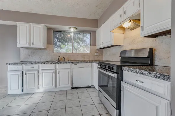 a kitchen with white cabinets and appliances