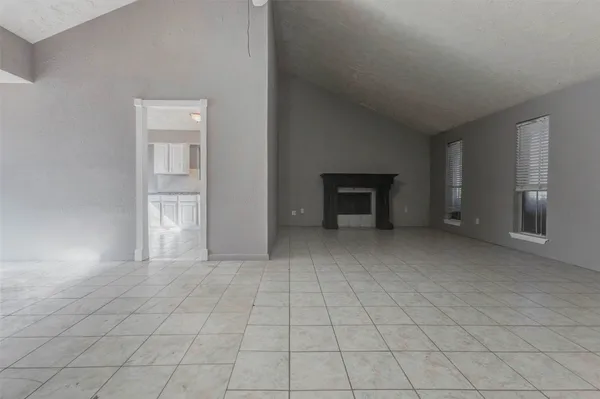an empty room with fireplace and natural light