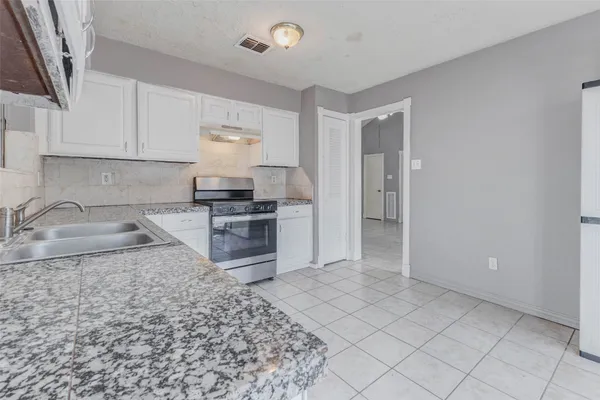 a kitchen with stainless steel appliances granite countertop a sink stove and cabinets