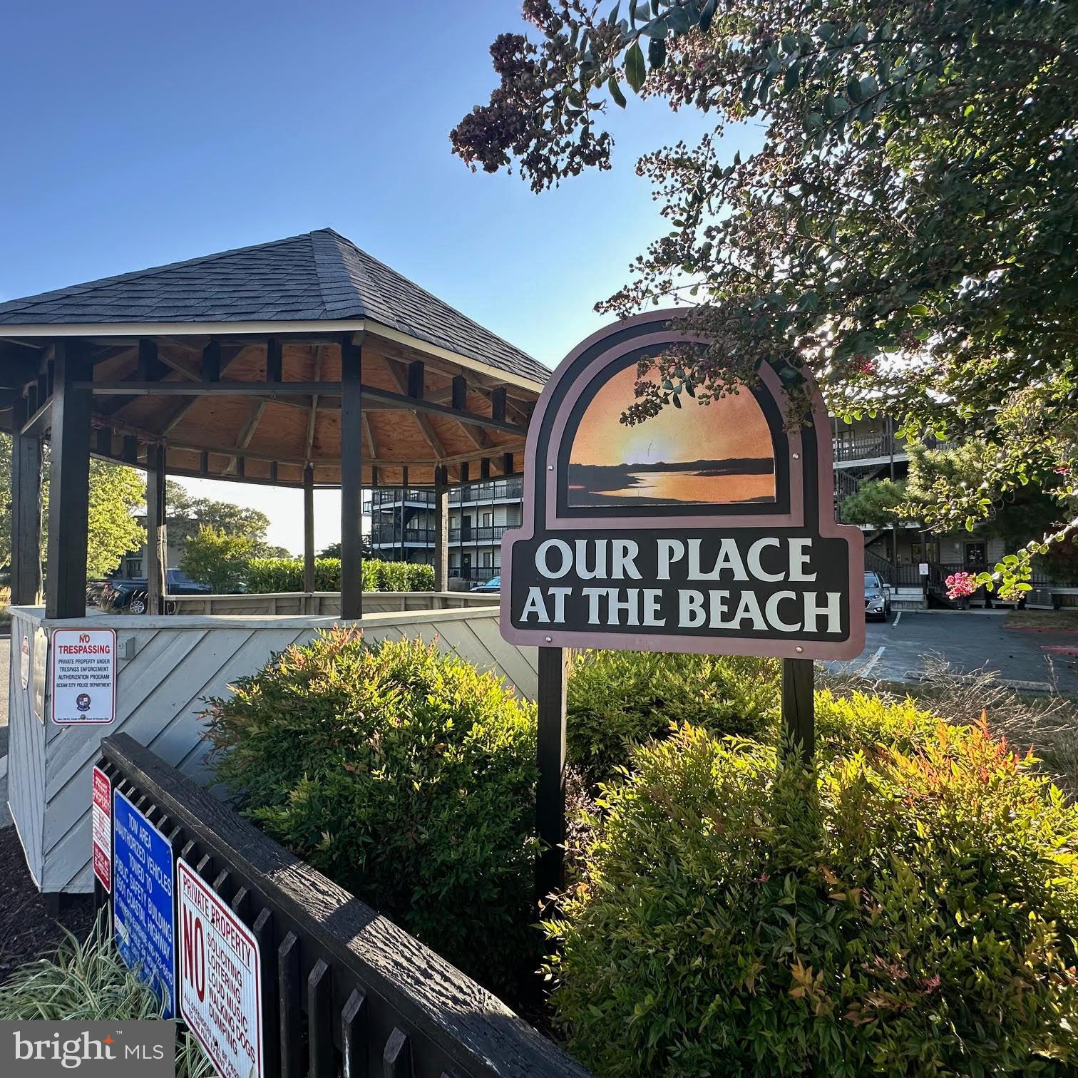 119 Old Landing Road, Unit E203 Ocean City, MD 21842 - Photo 5 of 45 a view of a garden with a bench under an umbrella